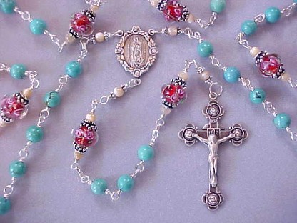 Genuine turquoise gemstone rosary with hand made red glass with pink roses, all sterling wire wrapped construction, sterling silver crucifix and Our Lady of Guadalupe center medal Genuine turquoise gemstone rosary with hand made red glass with pink roses, all sterling wire wrapped construction, sterling silver crucifix and Our Lady of Guadalupe center medal