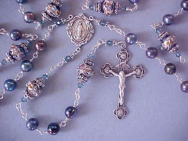 Iridescent twilight pearls shimmer with blue, teal, purple and copper tones combine with midnight blue lampworked glass, sterling silver rose crucifix and center, all sterling silver wire wrapped construction Iridescent twilight pearls shimmer with blue, teal, purple and copper tones combine with midnight blue lampworked glass, sterling silver rose crucifix and center, all sterling silver wire wrapped construction